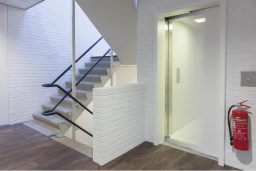 Unfurnished office interior at Pompmolenlaan 9 features an elevator and staircase, ideal for office space rental.
