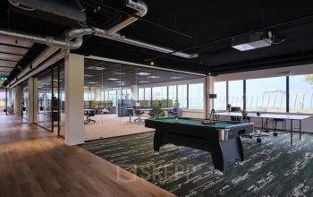 Spacious office at Vijzelmolenlaan 9, Woerden, featuring open-floor workspaces and a recreational area with a pool table. Ideal for office space rental.