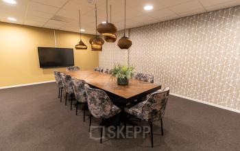 Furnished office space rental at Vijzelmolenlaan 9, Woerden, featuring a conference table and overhead lighting, ideal for meetings with AV equipment available.