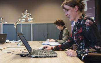 Two business professionals working on laptops in a furnished office at Zaagmolenlaan 4, Woerden. Office space rental available.