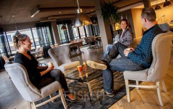 Office space rental at Zaagmolenlaan 4 in Woerden with three people engaged in a business discussion seated on modern chairs around a glass coffee table.