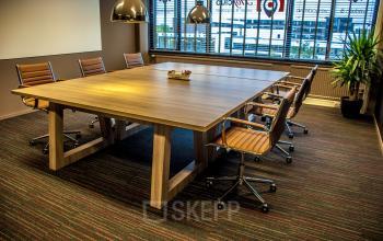 Conference room at Zaagmolenlaan 4, Woerden, with a large wooden table, leather chairs, and modern lighting.