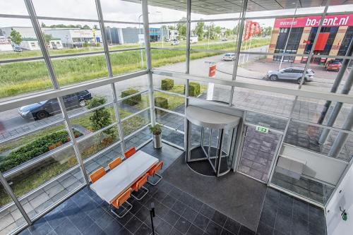 Spacious entrance area at Oude Blaauwweg 5, Wormerveer, featuring glass walls with natural light, a meeting table with orange chairs, and access to office space rental.