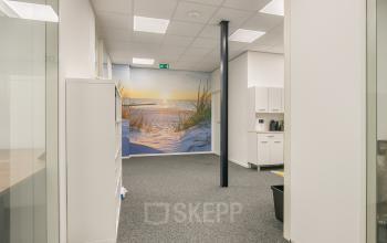 Bright office space at Huis ter Heideweg 24, Zeist featuring a sunny beach mural, with carpeted floors and minimal furnishings ideal for office space rental.