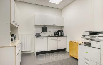 Interior view of a furnished office pantry at Huis ter Heideweg 24, Zeist, available for office space rental. Equipped with kitchen appliances and a multifunction printer.