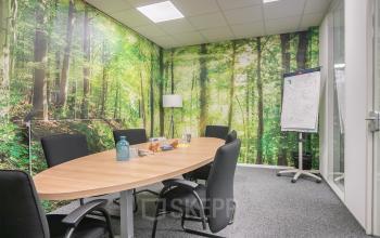 Bright office space with nature-themed wallpaper at Huis ter Heideweg 24, Zeist. Conference setup with a large table and chairs. Ideal for office space rental.
