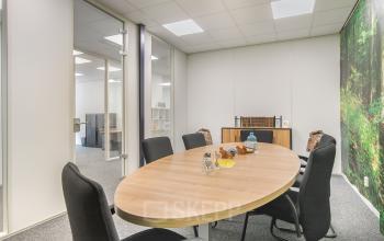 A furnished conference room with a large oval table and black chairs, located at Huis ter Heideweg 24 in Zeist, perfect for rent office space opportunities.