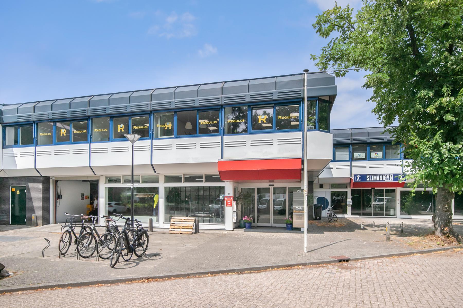 Exterior view of office building at Huis ter Heideweg 24, Zeist, showing multiple windows and a bike stand for office space rental.