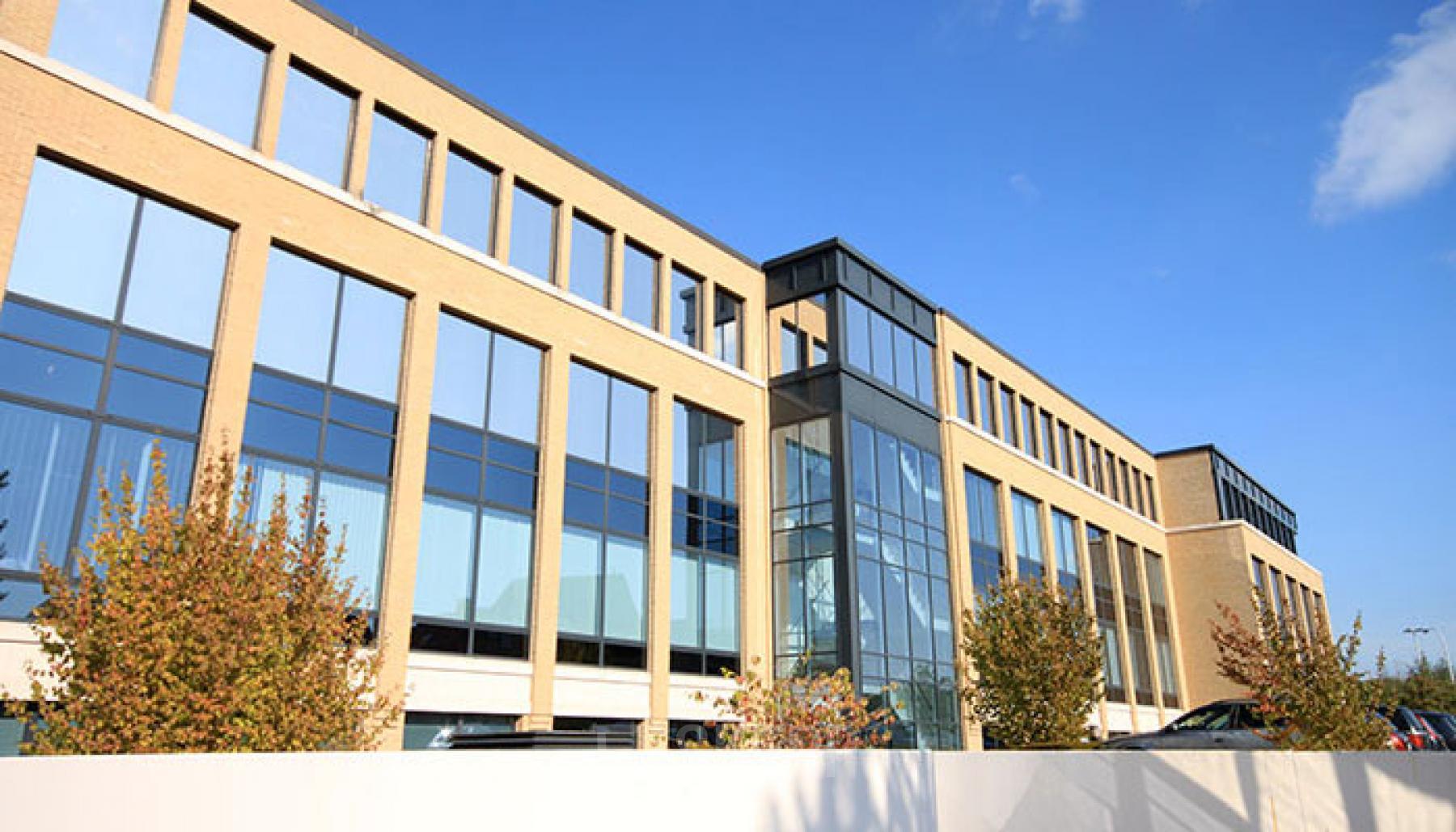 Exterior view of the office building located at Zuiderlaan 91, Zellik. The modern structure features large windows and a prominent glass entrance. Office space rental available here.