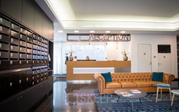 Reception area of an office space rental at Boerhaavelaan 40, Zoetermeer. Features a modern design, reception desk, mailboxes on the left, and a comfortable seating area with a brown sofa.