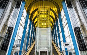 Grand entrance of the office building at Boerhaavelaan 40, Zoetermeer, with modern escalators and yellow glass canopy reflecting the exterior facade.