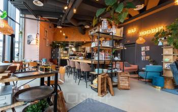 A trendy office space with modern furnishings, bar stools, and plants, located at Boerhaavelaan 40, Zoetermeer. Ideal for those seeking office space rental.