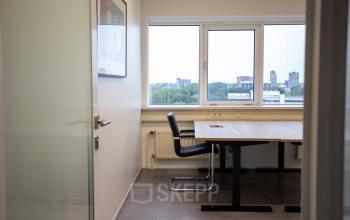 Office space rental at Boerhaavelaan 40, Zoetermeer, featuring a well-lit workspace with modern furniture, large windows, and a minimalistic design.