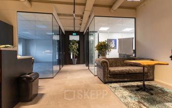 Office to rent at Boerhaavelaan 40 in Zoetermeer featuring a cozy furnished interior with a sofa and a wooden table, surrounded by glass-walled rooms and decorative plants.