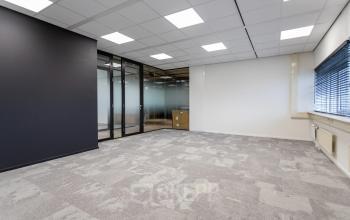 Spacious office to rent at Boerhaavelaan 40, Zoetermeer, featuring sleek glass partitions and modern ceiling lighting, ideal for setting up your professional workspace.