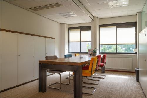 Bright, furnished office space available for rent at Bredewater 26, Zoetermeer, featuring a wooden table, diverse chairs, and large windows for natural light.