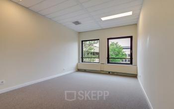 Bright interior of an unfurnished office space at Edelgasstraat 101 in Zoetermeer, featuring large windows with a view of outside greenery.