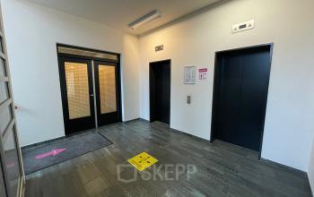 Office entrance area at Baron de Coubertinlaan 35, Zoetermeer, shown with elevators and directional signs, ideal for office space rental needs.