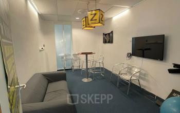 Cozy furnished office space at Baron de Coubertinlaan 35, Zoetermeer featuring seating, a television, and a unique decor, ideal for meetings or casual work sessions.