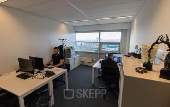 Professional office space rental with large window, desks, and computers at Louis Braillelaan 80, Zoetermeer.