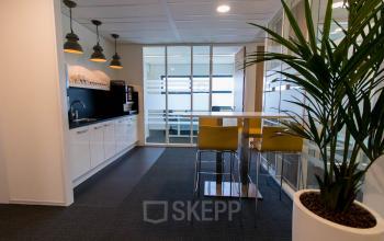 Modern office pantry at Louis Braillelaan 80, Zoetermeer, with white counters, bar stools, and potted plants.