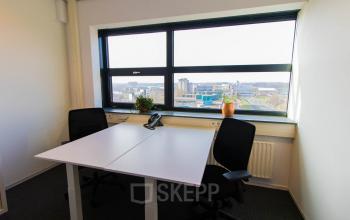 Modern office to rent at Louis Braillelaan 80, Zoetermeer, featuring a bright workspace with two desks, chairs, and large window with city view.