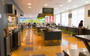 Spacious dining area with several food stations and people enjoying meals in the office at Louis Braillelaan 80, Zoetermeer.