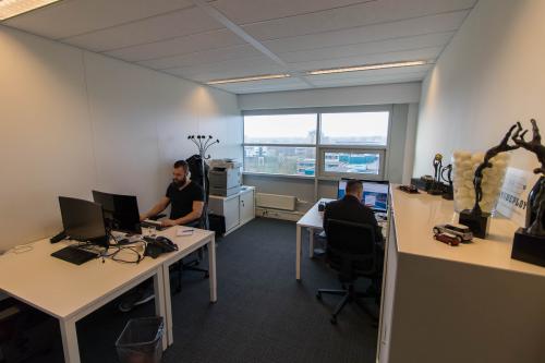 Professional office space rental with large window, desks, and computers at Louis Braillelaan 80, Zoetermeer.