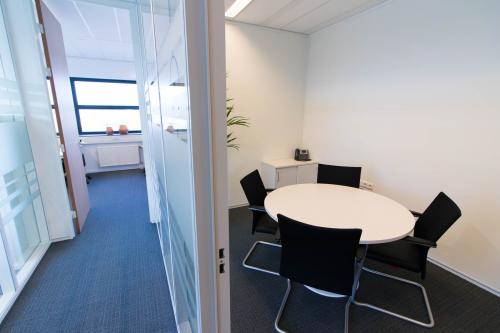 Interior view of office space for rent at Louis Braillelaan 80, Zoetermeer, featuring a glass-walled room with a round table and chairs.