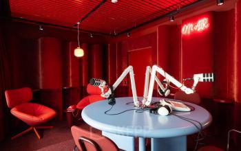 Modernes, rot gestaltetes Büro zur Miete mit Tisch und Mikrofonen in Zürich Enge, ideal für kreative Arbeitsumgebungen.