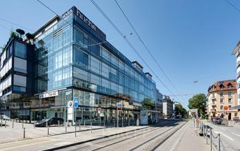 Modern office space rental at Badenerstrasse 549 in Zürich Old Town with a glass facade and tram lines in front.