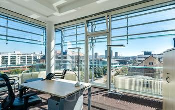 Bright office space rental at Badenerstrasse 549, Zürich Old Town, with large windows and a modern desk setup.