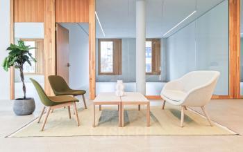 Moderne, minimalistische Lounge im Bürogebäude Zürcherstrasse 39d in Zürich Altstetten. Helle Möbel vor verglaster Wand, ideal für entspannte Gespräche. Perfekt für Büroraum mieten.