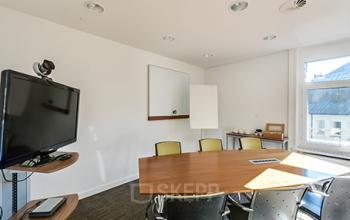 Modern ausgestatteter Besprechungsraum zur Miete am Bahnhofplatz 1 in Zürich City, mit Konferenztisch, Stühlen und Präsentationstechnik.