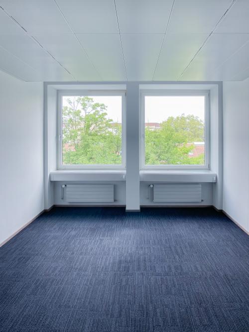 Helles, leeres Büro zur Miete in der Löwenstrasse 29, Zürich City, mit Teppichboden und großen Fenstern mit Ausblick ins Grüne.