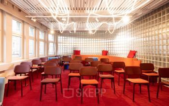 Büroraum in Zürich City an der Uraniastrasse 31 mit leeren Stühlen in einem Raum mit rotem Teppich und moderner Beleuchtung, ideal zum Büro mieten.