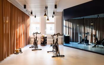 Innenraum in der Uraniastrasse 31, Zürich City; heller Raum mit Spiegeln und Fitnessgeräten, ideal für Bürofläche mieten. Gemütliche Atmosphäre mit modernen Lampen und eleganten Vorhängen.