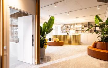 Modernes Bürolobby mit Sitzgelegenheiten in der Uraniastrasse 31, Zürich City, mit goldener Rezeptionstheke. Perfekt für alle, die Büroraum mieten möchten.