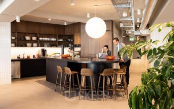 Moderne Bürofläche mieten in der Uraniastrasse 31, Zürich City. Zwei Personen arbeiten an einem stilvollen Gemeinschaftstisch in einer gut ausgestatteten Büro-Innenküche.