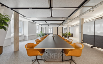 Moderner Konferenzraum in Zürich City, Talacker 21, mit langen Tisch und stilvollen orangefarbenen Stühlen; ideal für eine Bürofläche zu mieten.