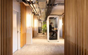 Moderner Büroraum in der Beethovenstrasse 48, Zürich Enge, mit Holzelementen und einer schallisolierten Kabine, ideal zum Büro mieten.