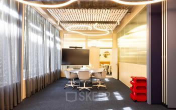 Modernes Büro zur Miete in der Beethovenstrasse 48, Zürich Enge, mit einem Konferenztisch und einem großen Bildschirm für Präsentationen.