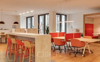 Modern office space rental at The Circle, Zürich Airport, featuring a bright workspace with orange chairs and neat lines.