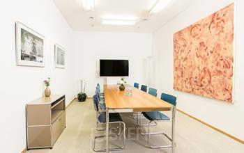 Well-lit conference room at The Circle, Zürich Airport, perfect for office space rental meetings, with a rectangular table, artwork, and a screen.