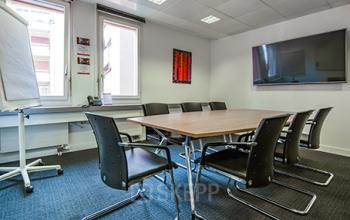 Well-equipped conference room available for office space rental at Seefeldstraße 69, in Zürich Riesbach, featuring a large table, chairs, and presentation tools.