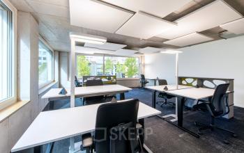 Moderne Büroräume in Zürich Seebach mit weißen Tischen und ergonomischen Stühlen, ideal um ein Büro zu mieten in Thurgauerstrasse 132.