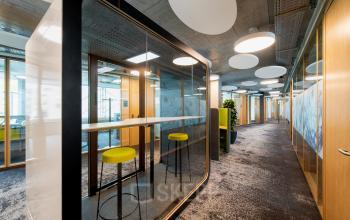 Moderne Bürofläche mieten in Thurgauerstrasse 132, Zürich Seebach, mit Glasabtrennungen und hohen Barhockern.