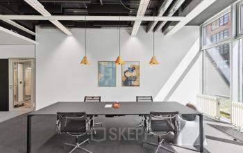 Helles Büro in der Elias-Canetti-Strasse 2, Zürich Seebach mit modernem Tisch und Stühlen, ideal zum Büroraum mieten. Kunstwerke an den Wänden schmücken den Raum.