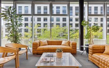 Moderner Büroraum in Zürich Seebach mit großen Fenstern, Ledersofas und Pflanzen; ideal für alle, die Bürofläche mieten möchten.