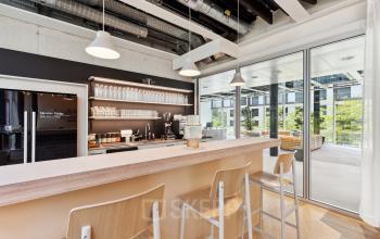 Moderne Bürofläche mieten in Zürich Seebach: Stylische Kaffeeecke mit hellem Interieur und großen Glasfronten für viel Tageslicht.